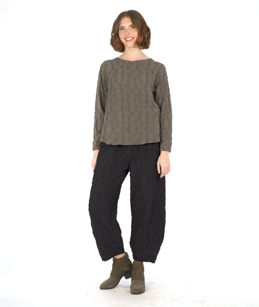 model wearing a green long sleeve top with matching wide leg black pants that taper to a tulip shape at ankle