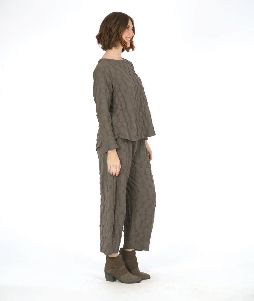 model wearing a green textured long sleeve top with matching wide leg pants that tapers to tulip shape at ankle on a white background