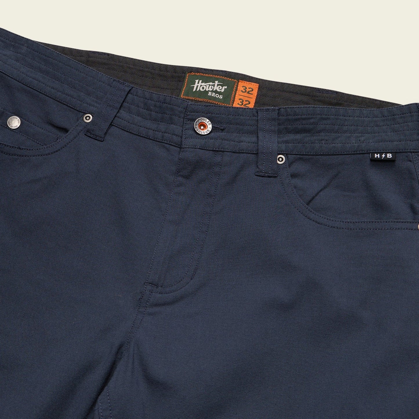 Navy blue pants with a brand label on a beige background