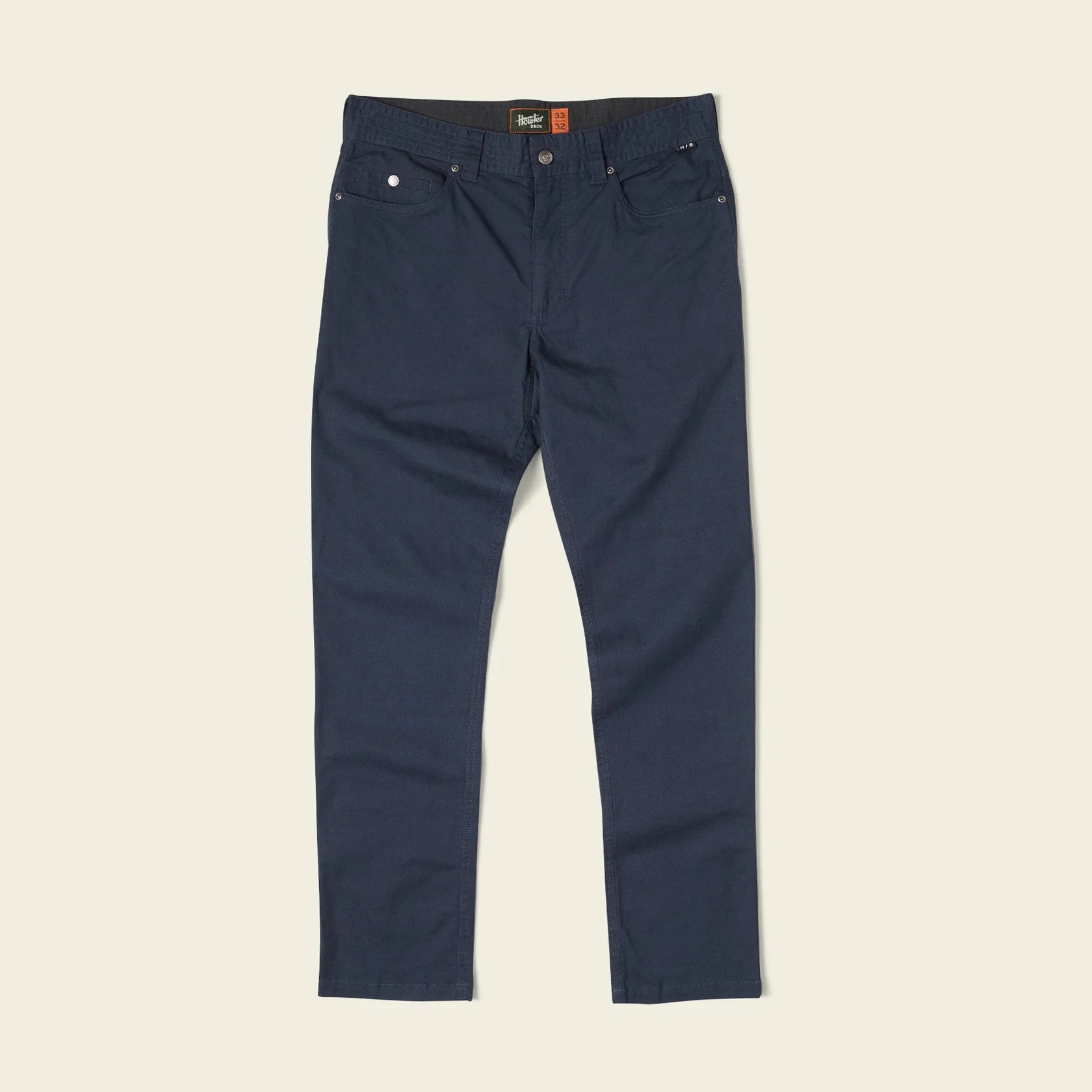 A pair of dark navy blue slim-fit jeans laid flat against a light beige background.