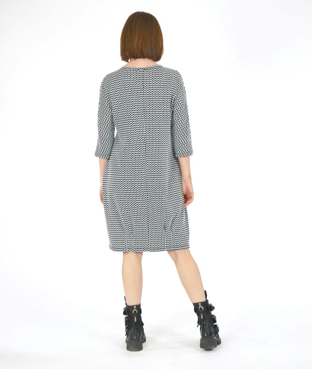 woman in a black and white knee length dress in a zipper stripe print. dress has shaping darts at the waist