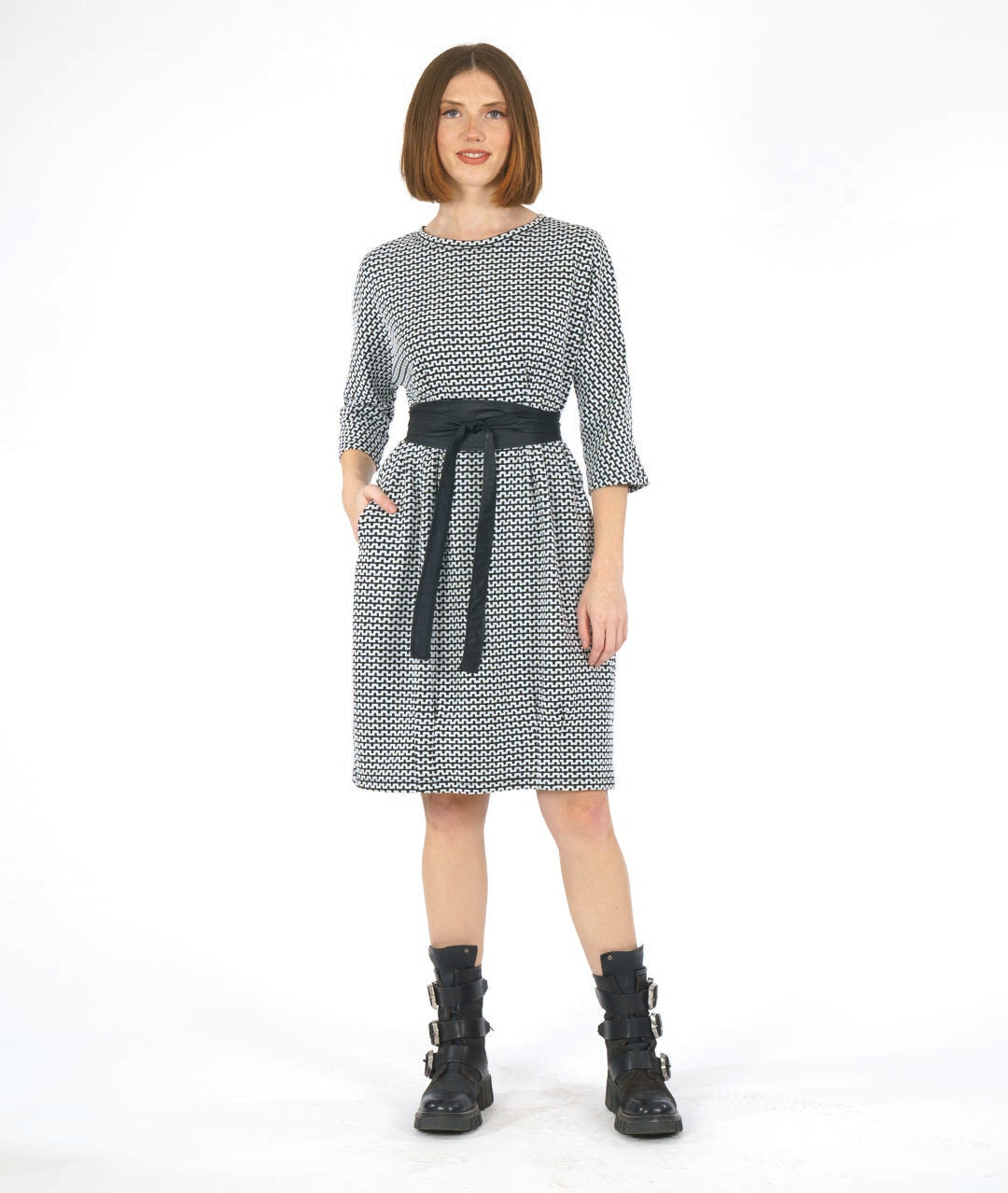 woman in a black and white knee length dress in a zipper stripe print. dress has shaping darts at the waist