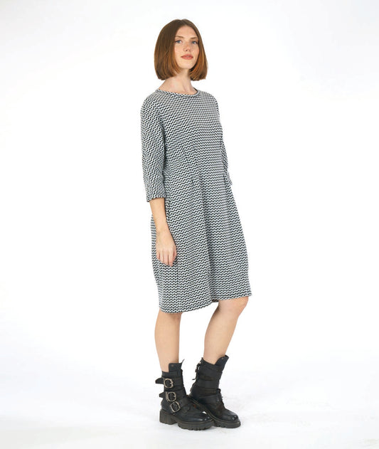 woman in a black and white knee length dress in a zipper stripe print. dress has shaping darts at the waist