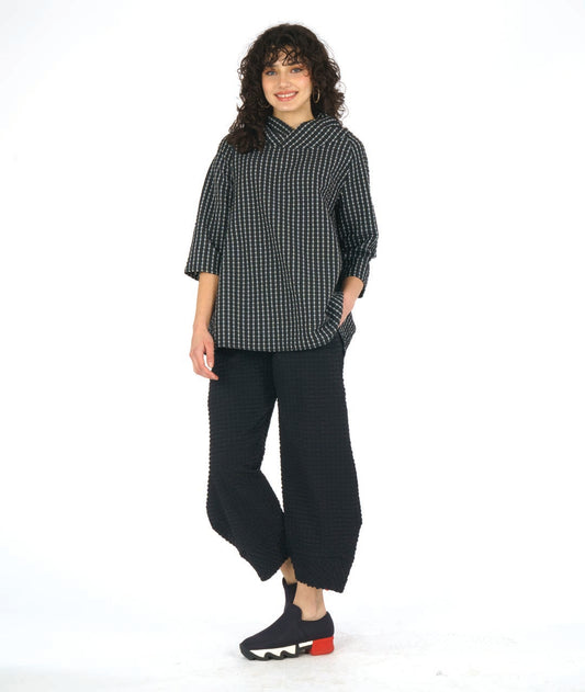 model in a wide leg black pant with a tapered ankle. worn with a black and white grid print pullover top with an oversized, gathered collar and 3/4 sleeves