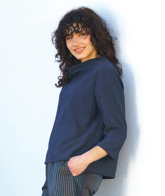model wearing a navy blue cowl top against a white background
