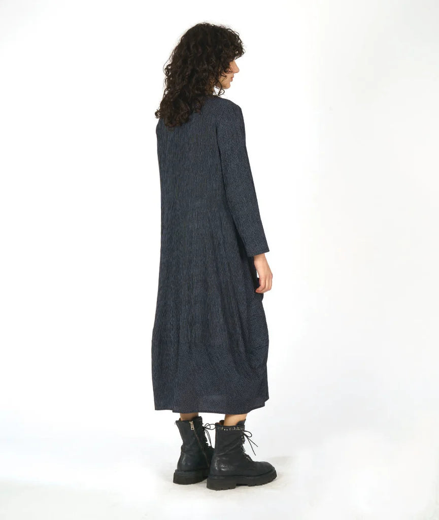 Woman wearing a long dark grey dress with a white background