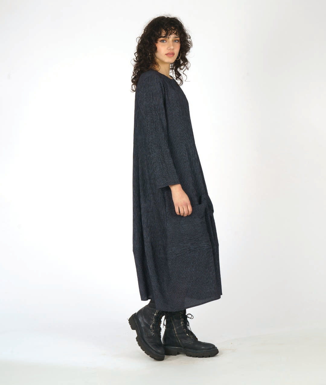 model in a black and grey dress with contrasting angled panels, oversized pockets, and long sleeves