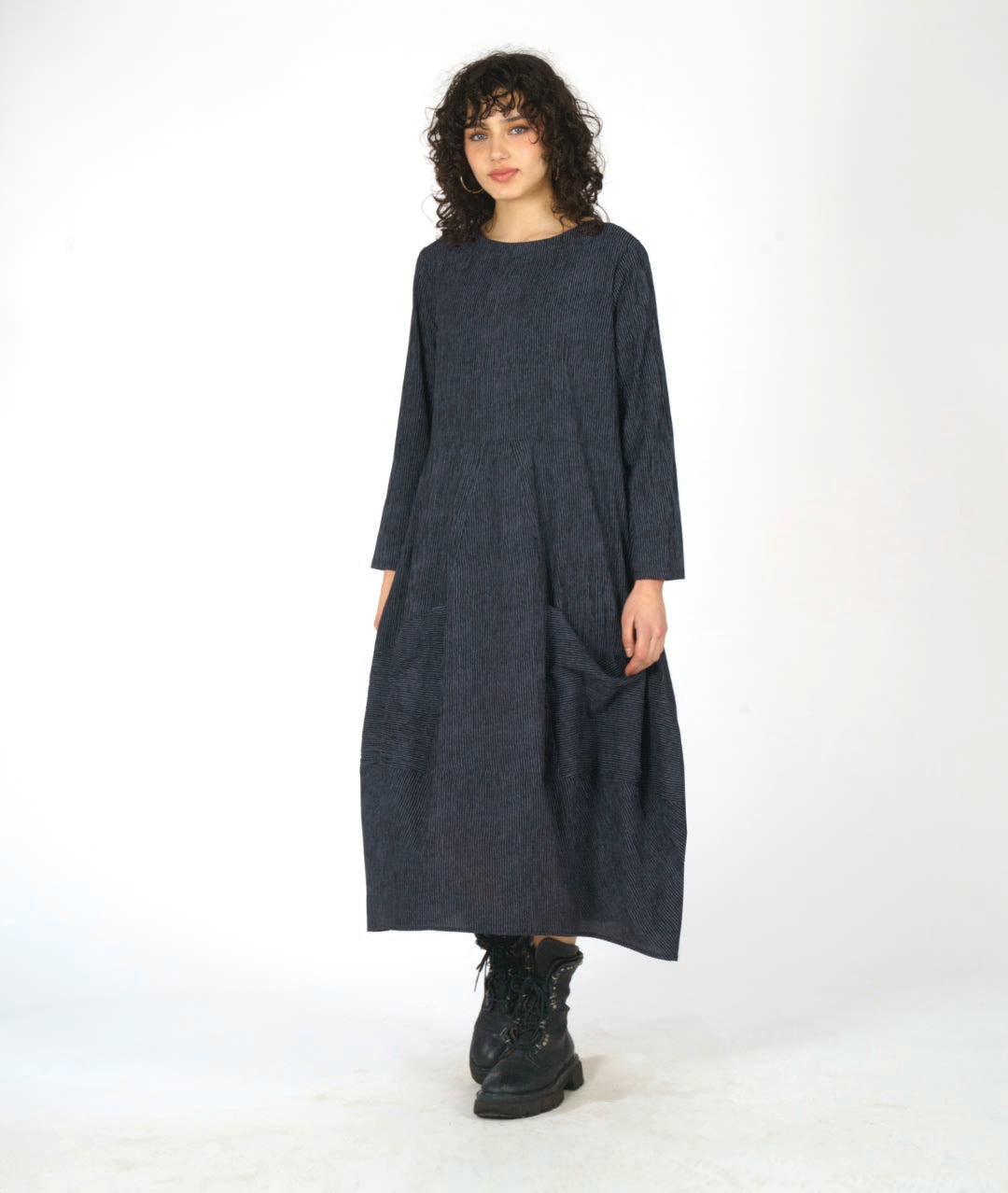 model in a black and grey dress with contrasting angled panels, oversized pockets, and long sleeves