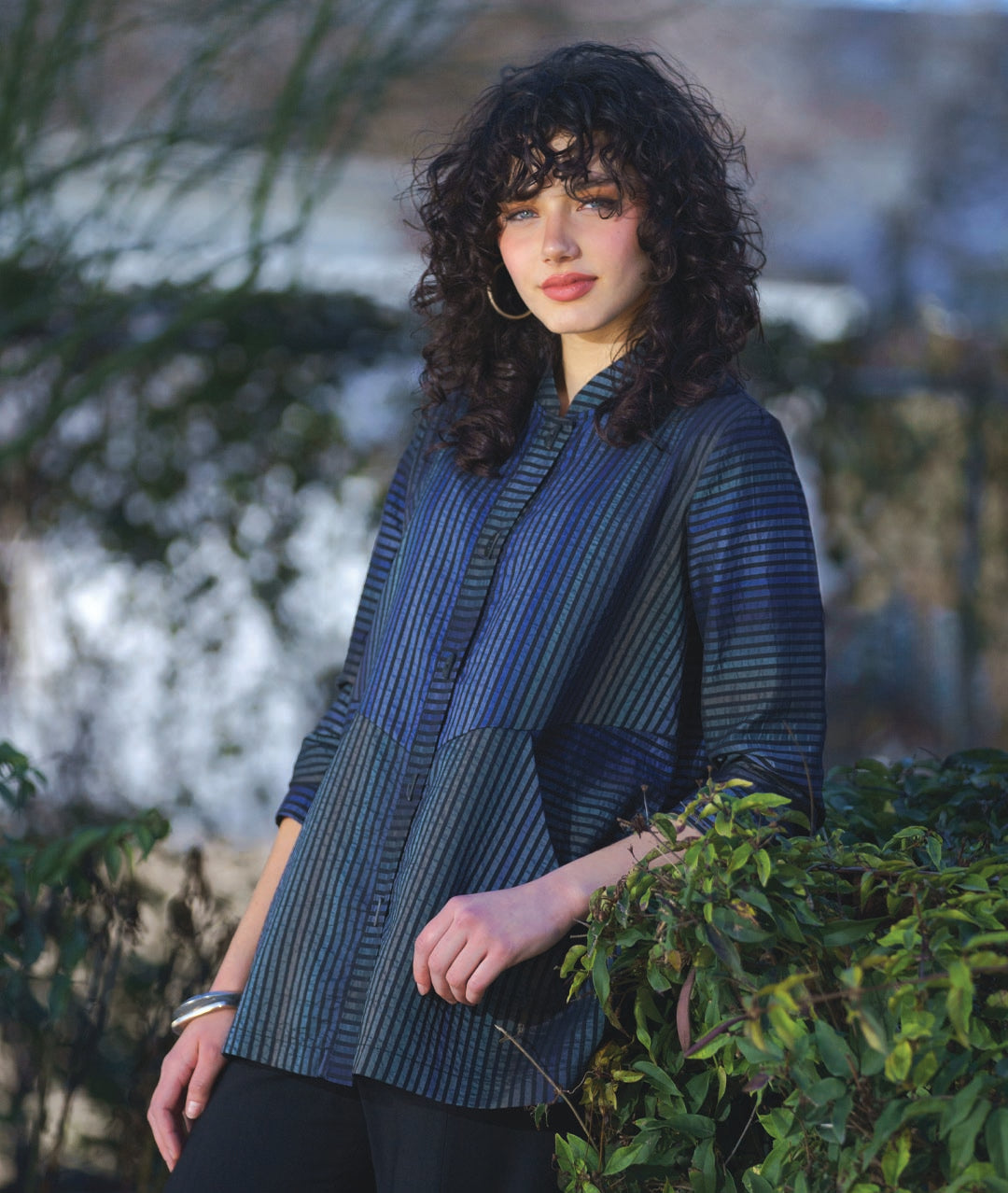 model in a multi tonal blue striped jacket with contrasting panels of stripe direction. worn with black pants