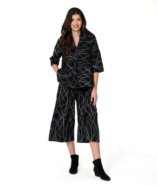 model in a wide leg black pant with a grey and blue multicolor stripe. worn with a matching boxy pullover with 3/4 sleeves and a collar