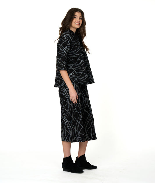 model in a wide leg black pant with a grey and blue multicolor stripe. worn with a matching boxy pullover with 3/4 sleeves and a collar