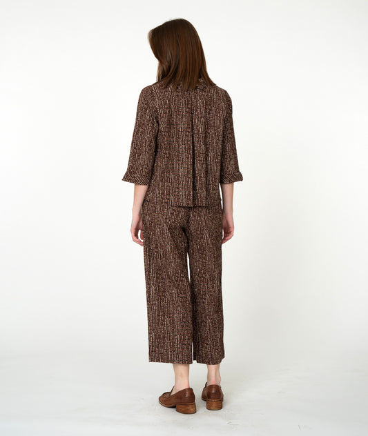 Woman wearing a brown patterned outfit on a white background