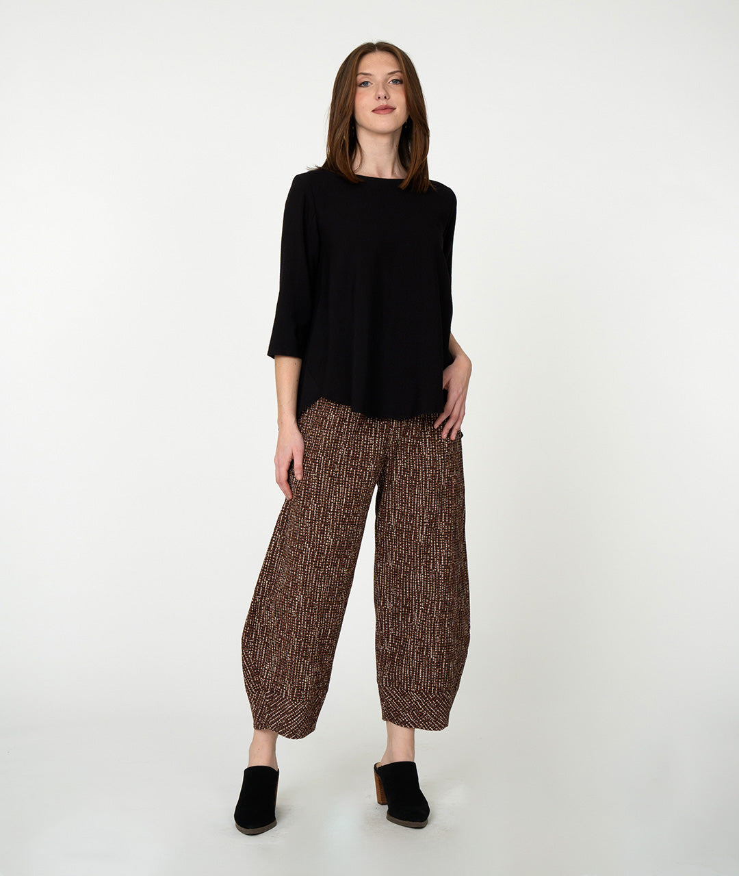 model in a black pullover top with a barrel leg brown and ivory striped pant