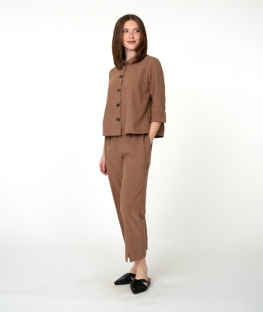 A woman modeling a matching brown two-piece set consisting of a button-front blouse with three-quarter sleeves and straight-leg cropped pants, paired with black flats, against a plain white studio background.