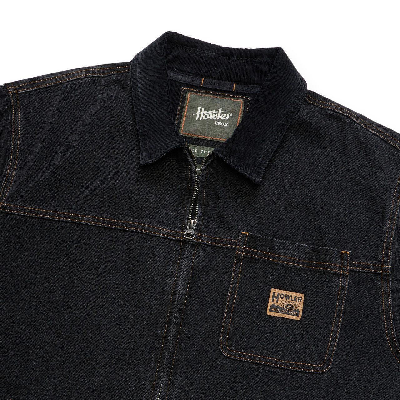 Close-up of a dark indigo denim work shirt by Howler, featuring a collar, half-zip front, and a chest pocket with a brand patch.