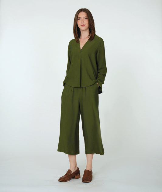 Woman wearing a green outfit with wide-leg pants on a white background