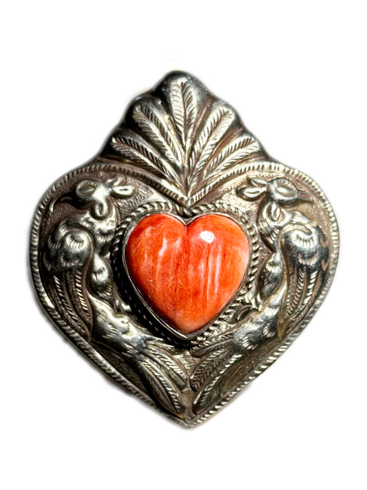 Decorative heart-shaped ring with a coral-colored center on a white background