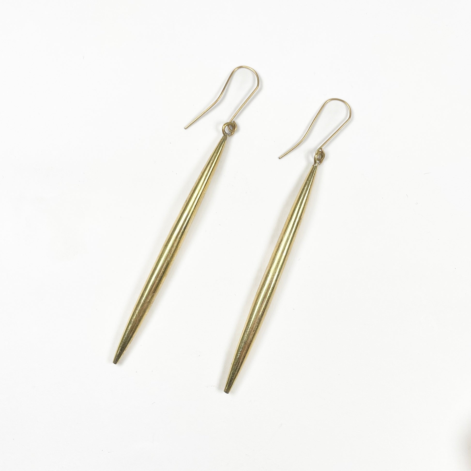 gold long cylindrical spike earrings on a white background