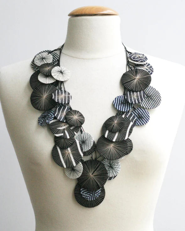 Black and white circle patterned necklace on a mannequin against a white background