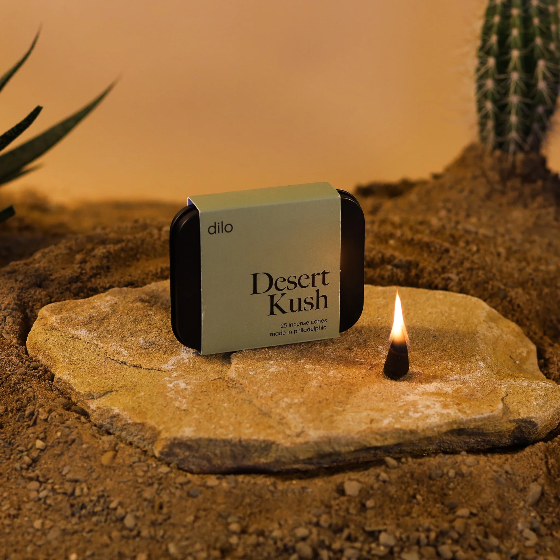 desert kush scented incense cone packaging with lit cone on a stone with desert background