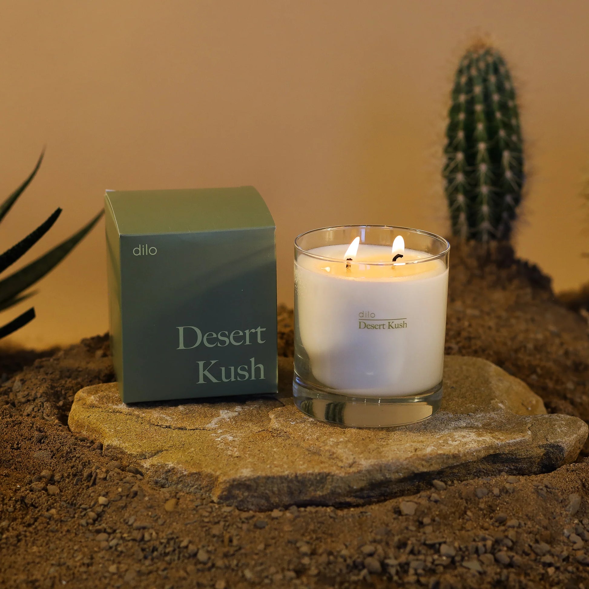 desert kush scented candle with packaging on rock and desert background