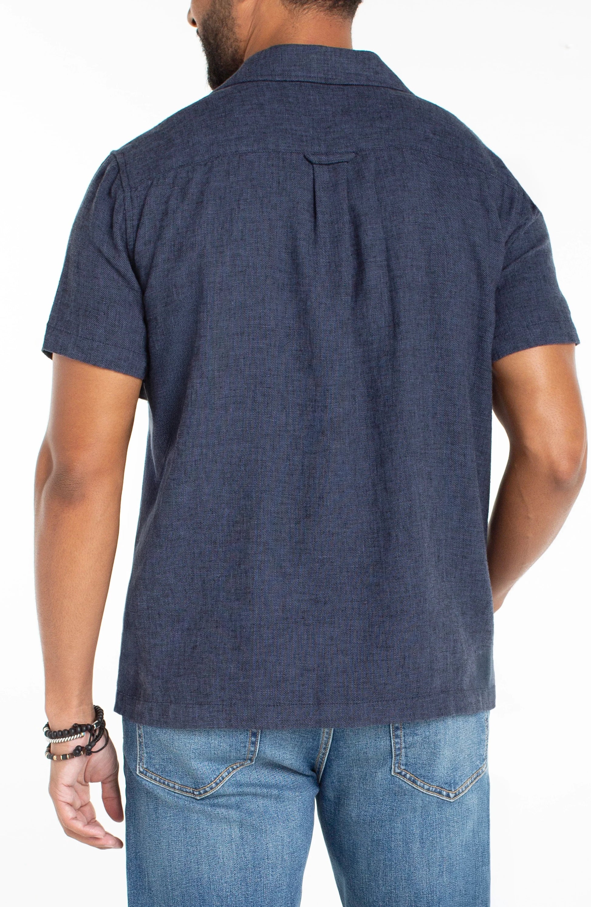 Man wearing a navy blue short-sleeve shirt and jeans on a white background