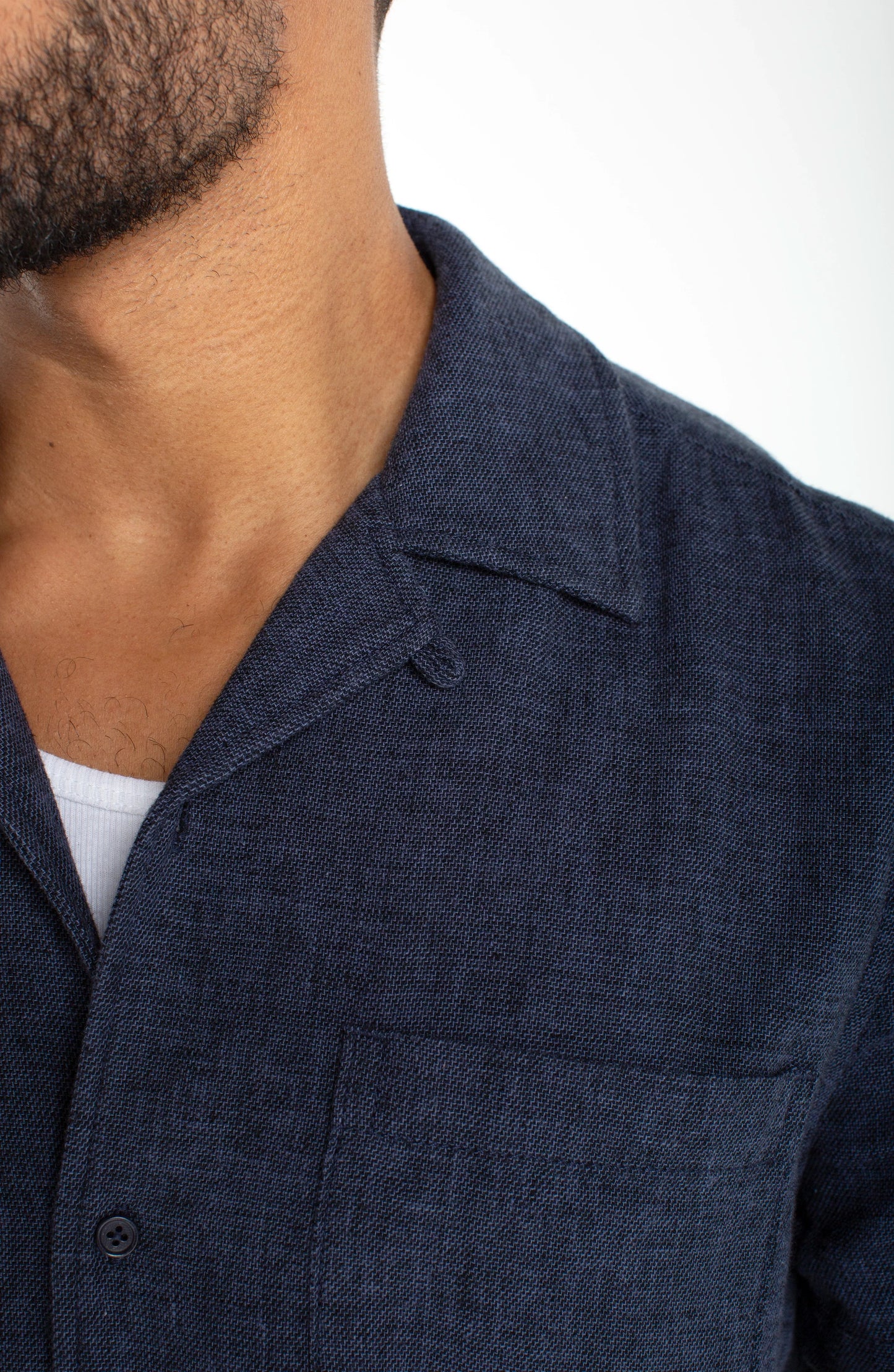 Close-up of a person wearing a dark blue jacket with a white background