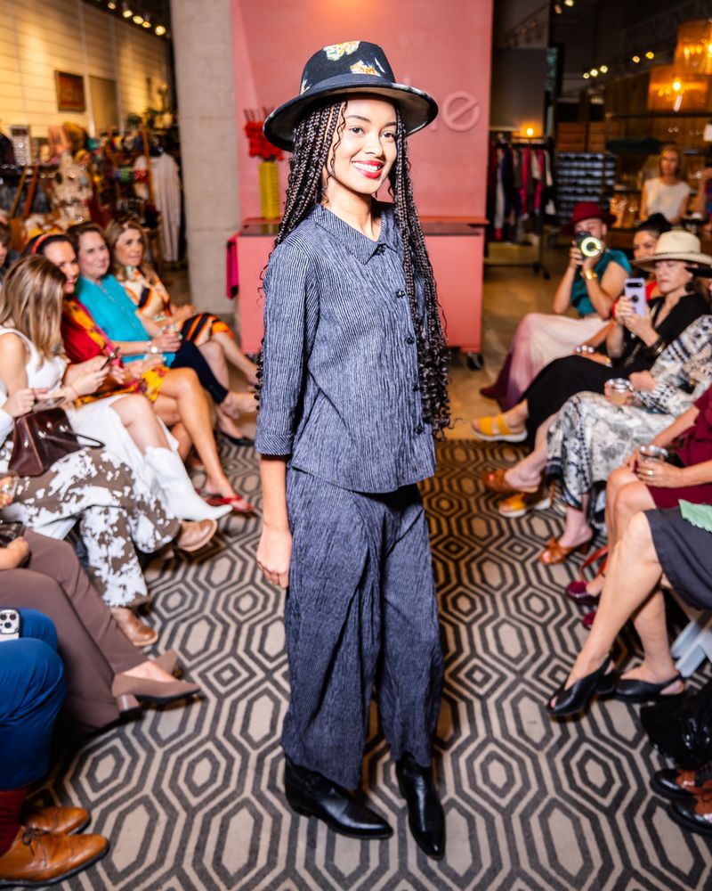 model in a matching grey stripe outfit and hat on a runway