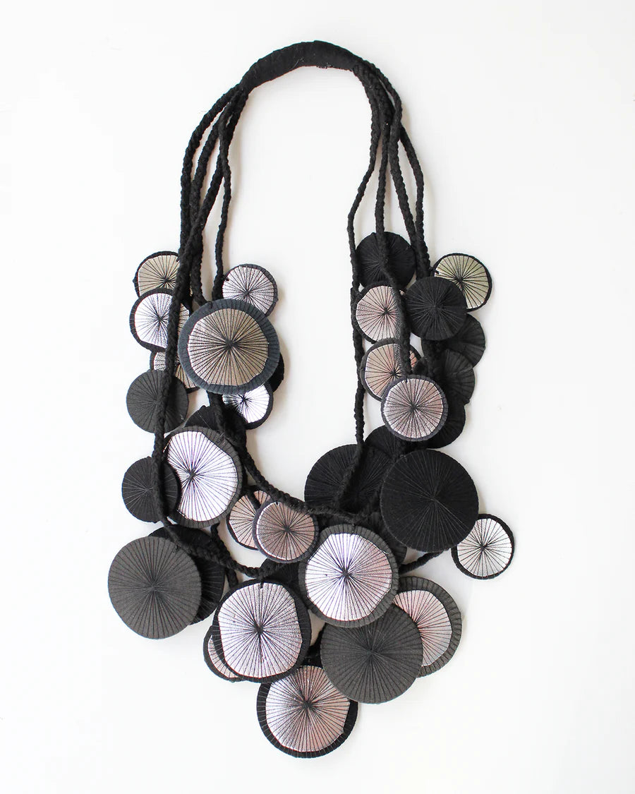 Necklace with circular black and white poms on a white background