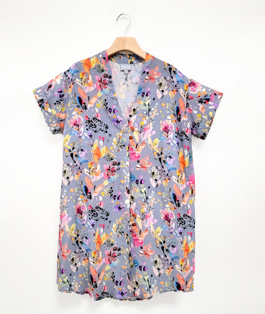 light grey boxy dress with colorful flowers, short cuffed sleeves, v-neck and rounded hem on a hanger.