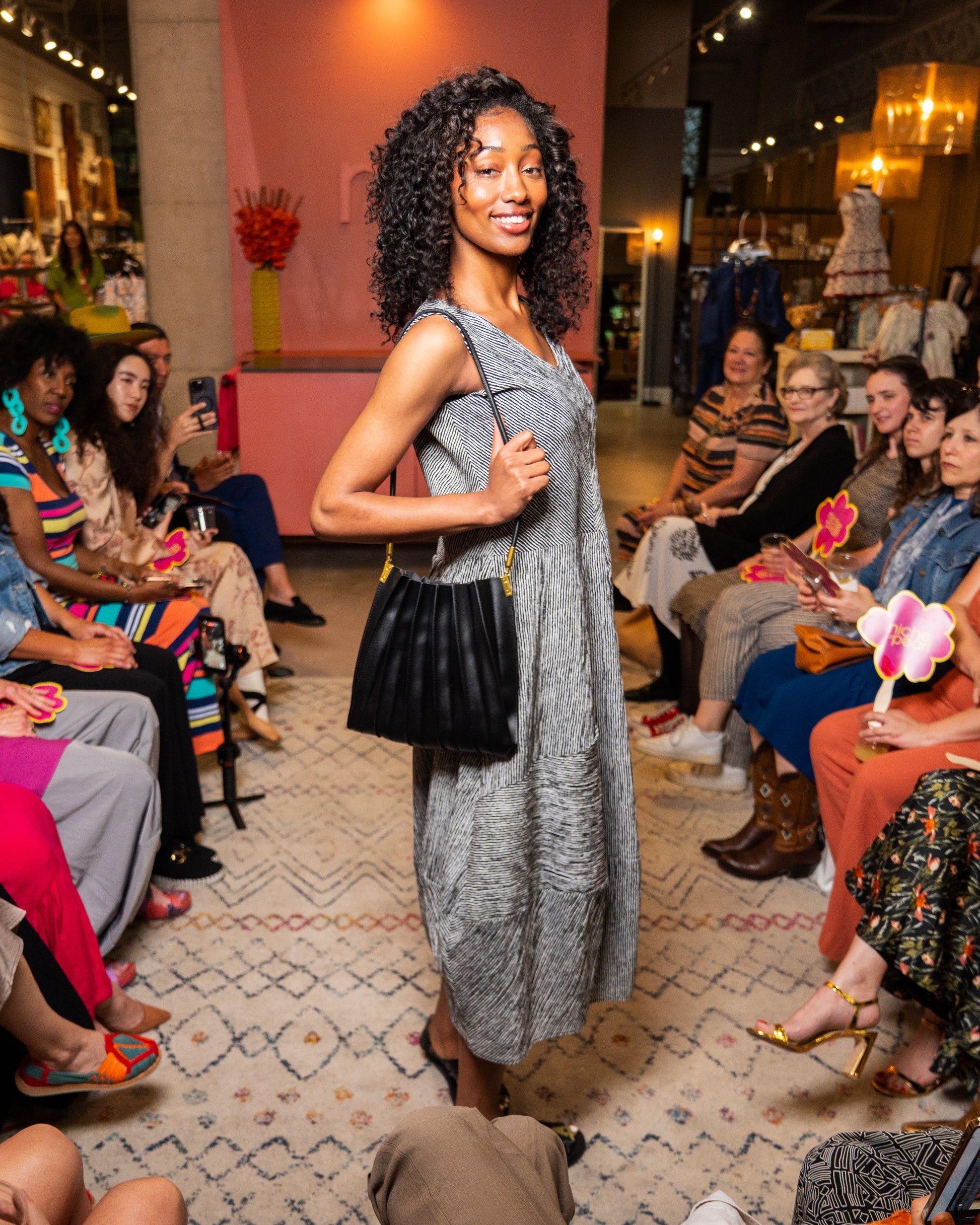 Woman in a black and white stripe dress and black purse walking down runway 