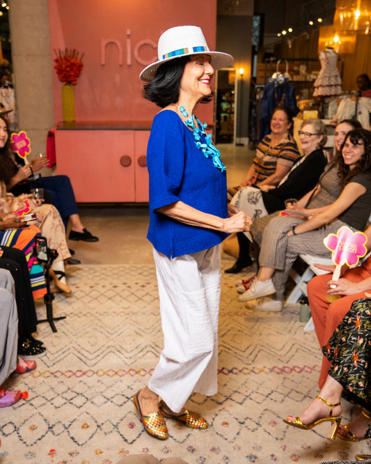 Woman in blue top and white pants with a hat
