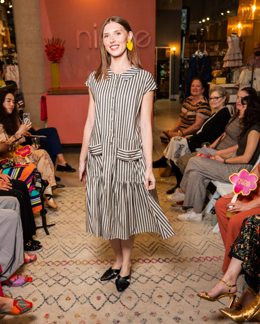 Woman in a striped dress standing in a fashion show setting 