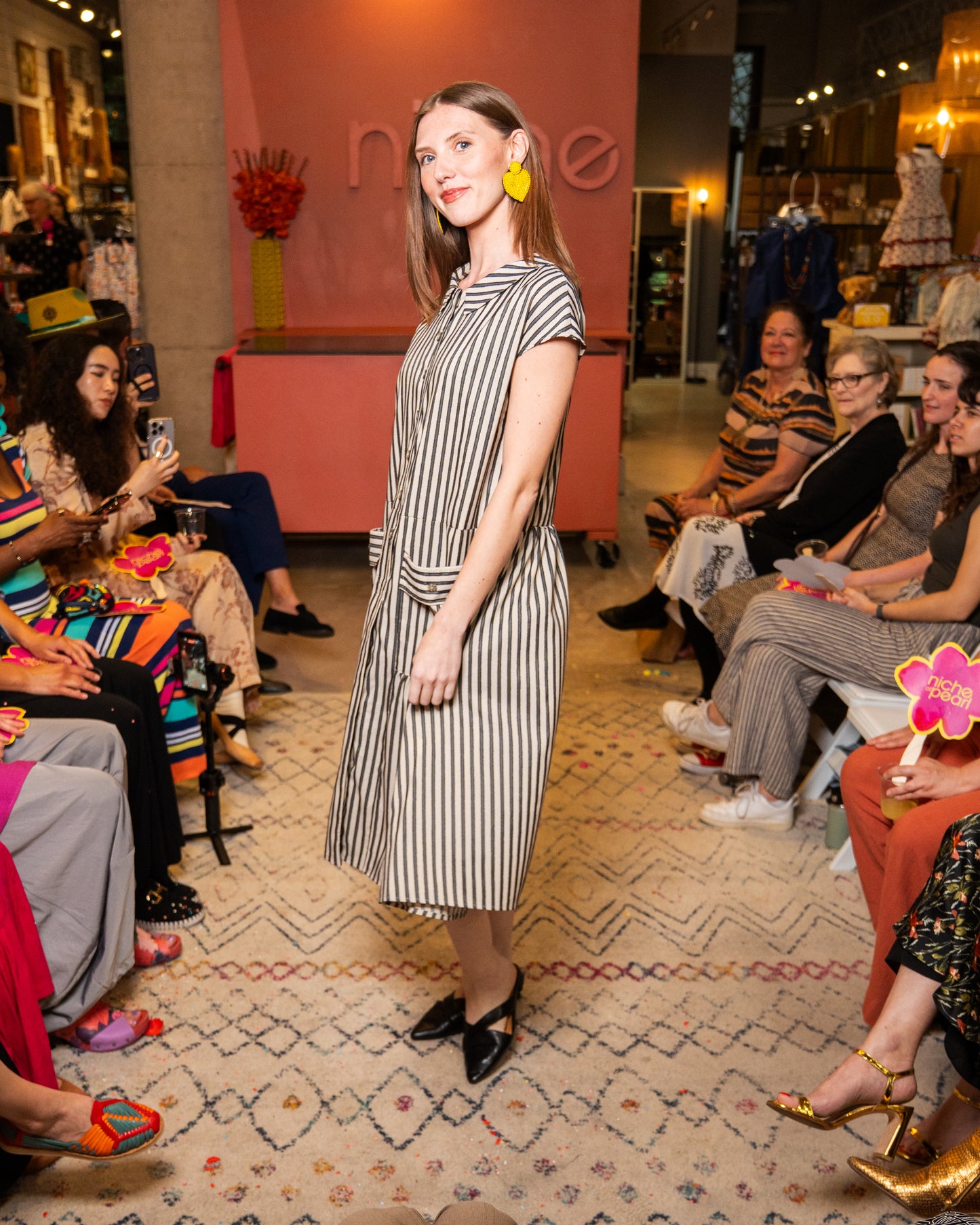 Woman in a striped dress standing in front of an audience at a fashion event.