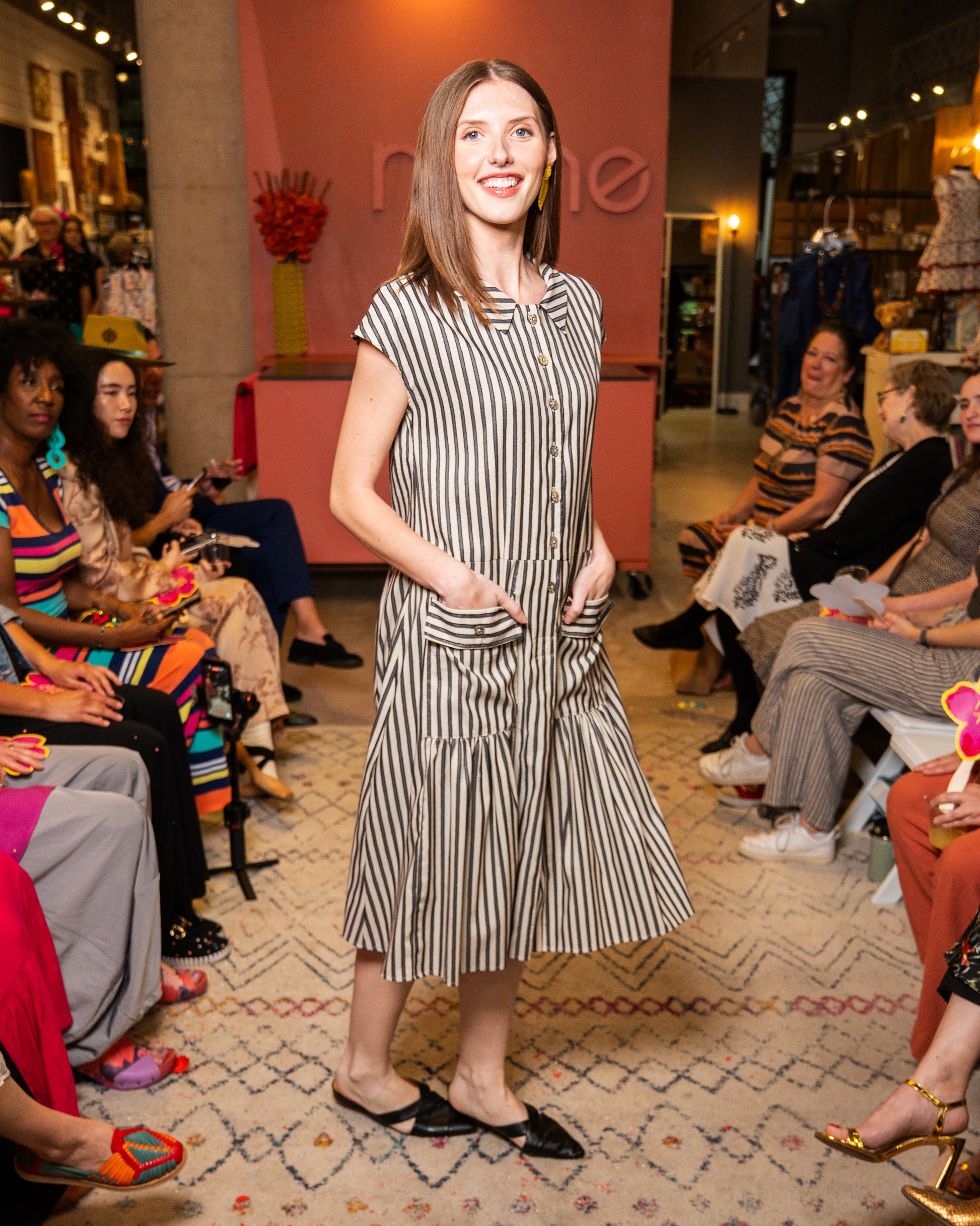 Woman in a striped dress standing in a store with people around