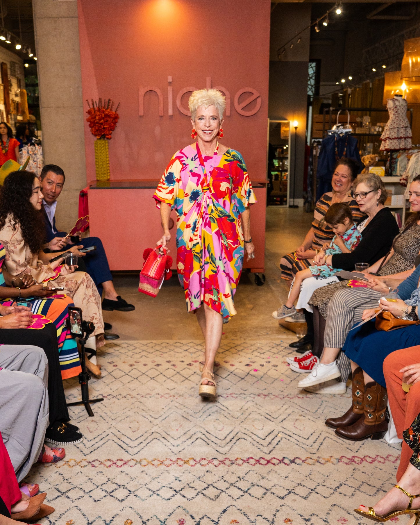 Model wearing a colorful dress walking on a fashion runway with 'niche' branding.