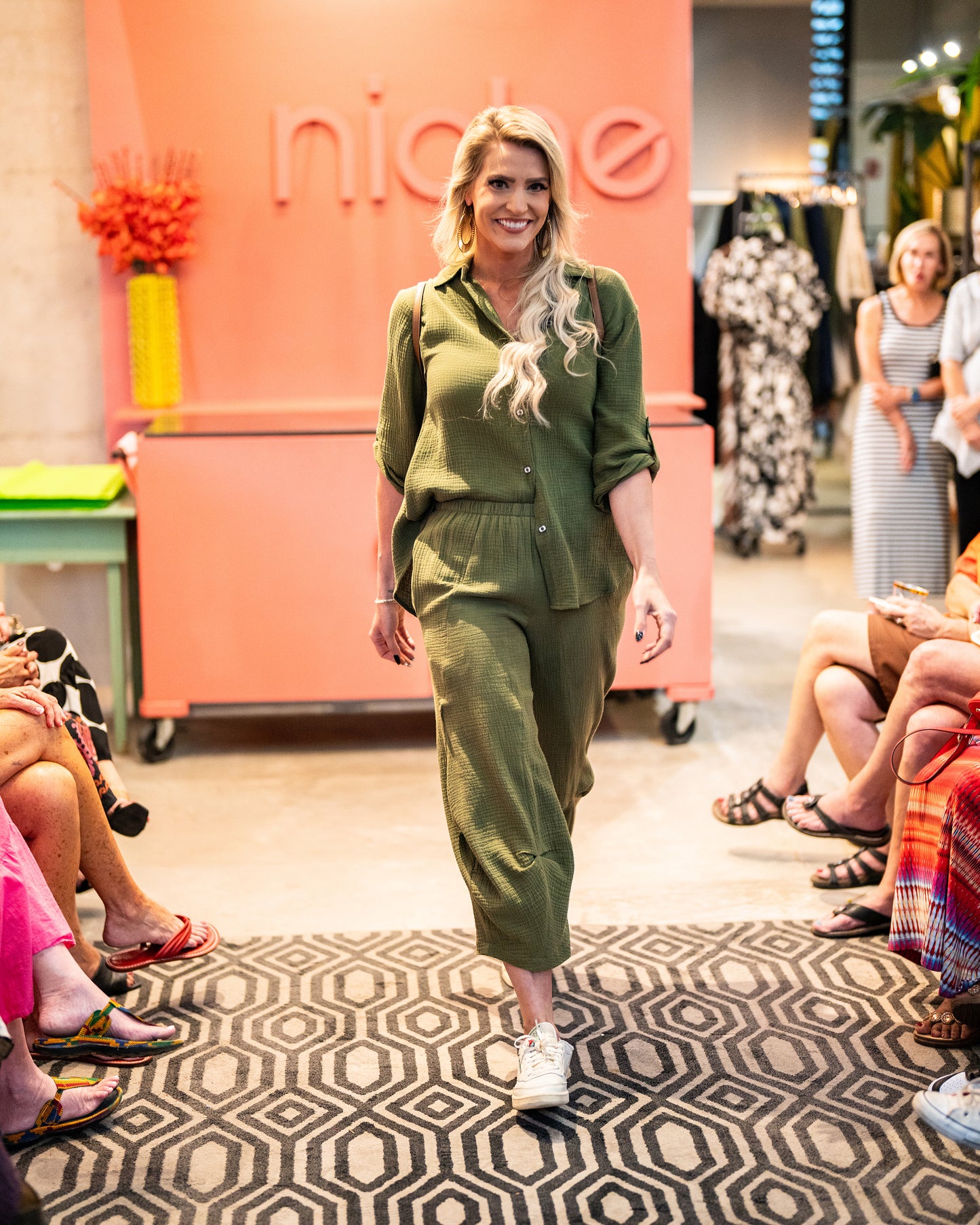 model in a green double gauze pant with a tuck at the front legs, worn with a matching button down blouse with a rolled and buttoned sleeve