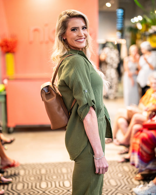 model in a green double gauze pant with a tuck at the front legs, worn with a matching button down blouse with a rolled and buttoned sleeve