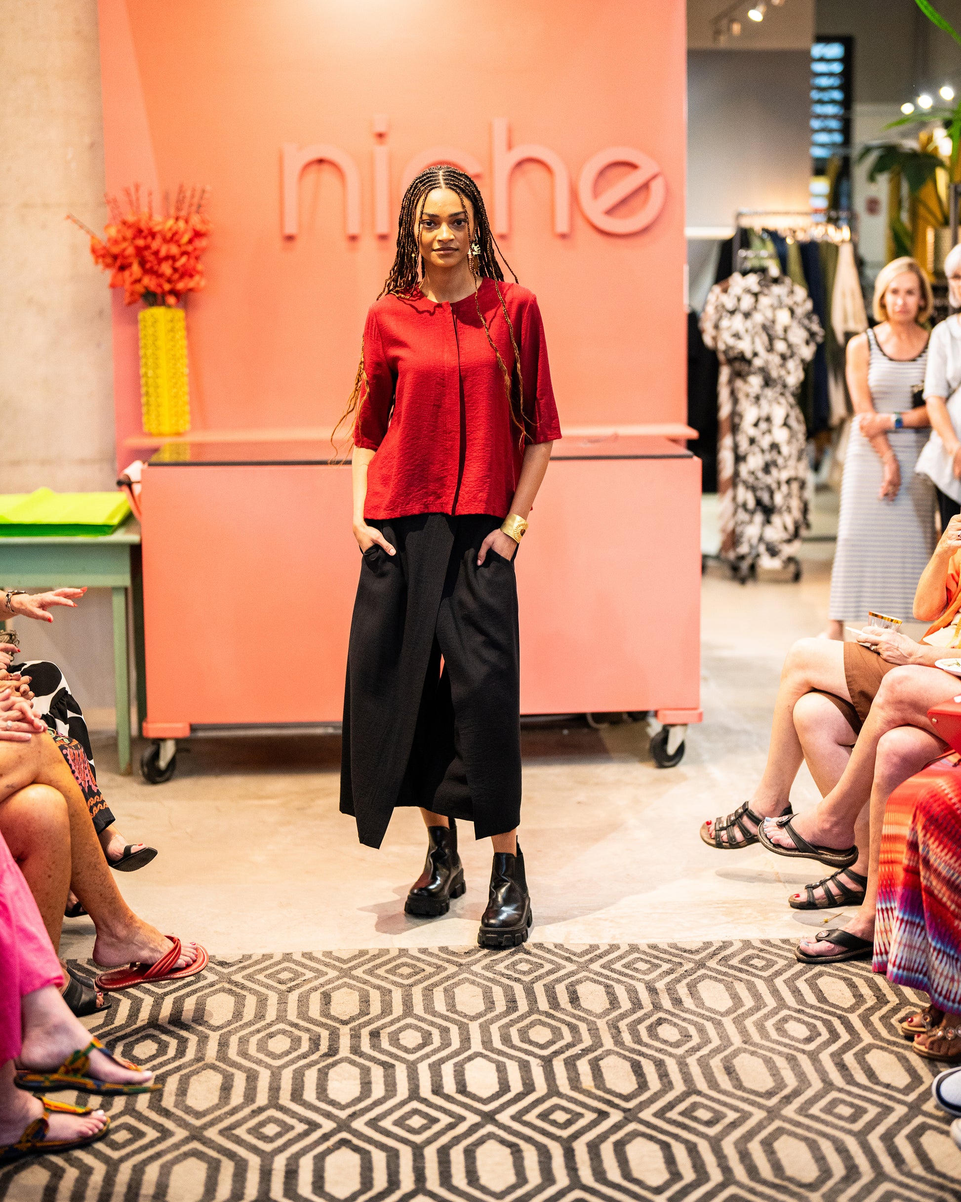 model in a wide leg black pant with a brick red top with a 3/4 sleeve and a hidden placket