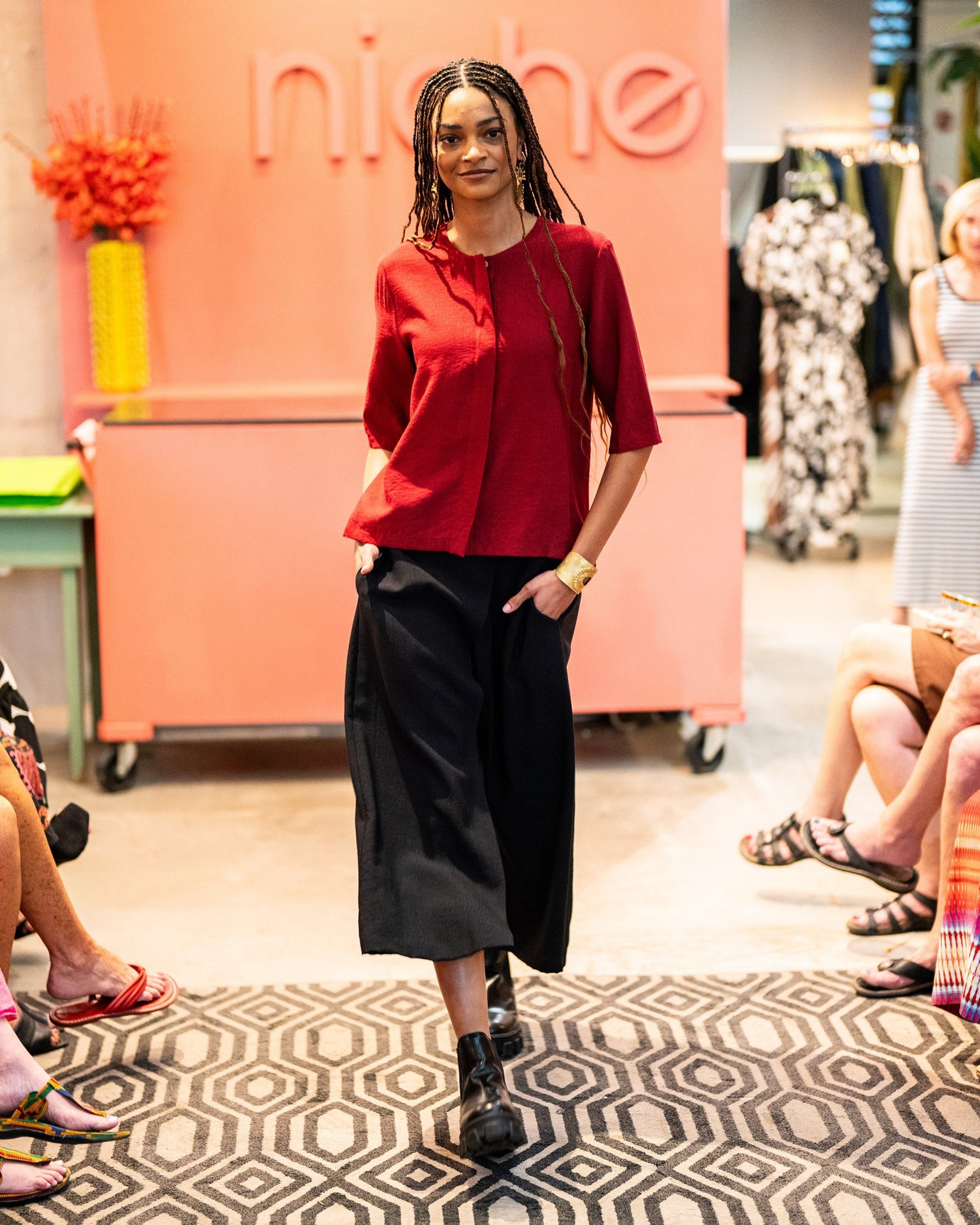 model in a wide leg black pant with a brick red top with a 3/4 sleeve and a hidden placket