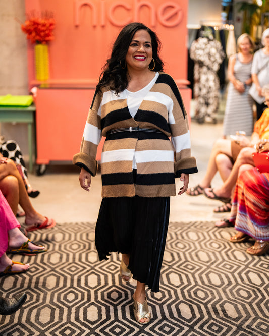 model in a black skirt with a white top under a black, white and brown striped cardigan