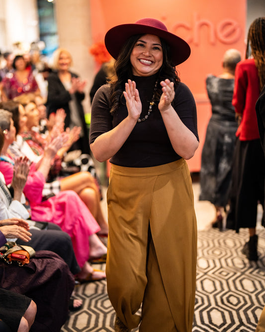 model in a wide leg ochre pant with a black tee and maroon hat