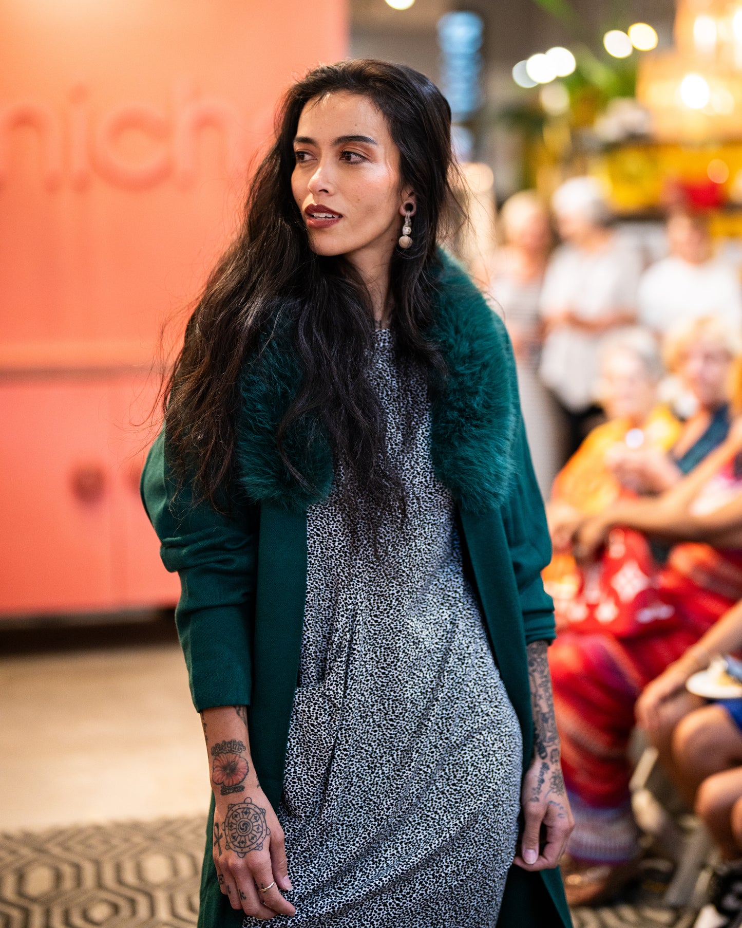 model wearing speckled dress with one front pocket and green cover up with fur collar