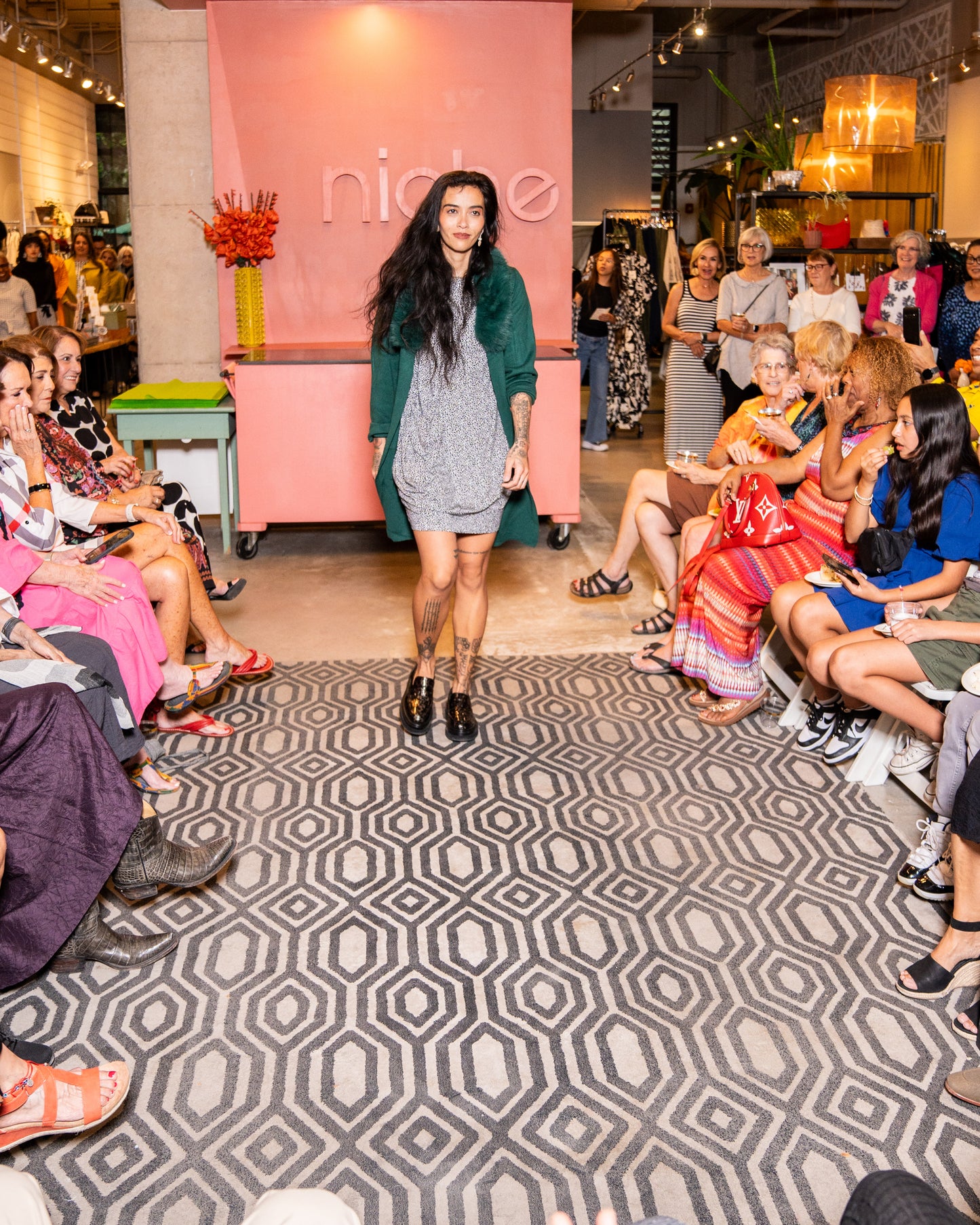 model walking down runway wearing speckled dress with a fur collar green cover up