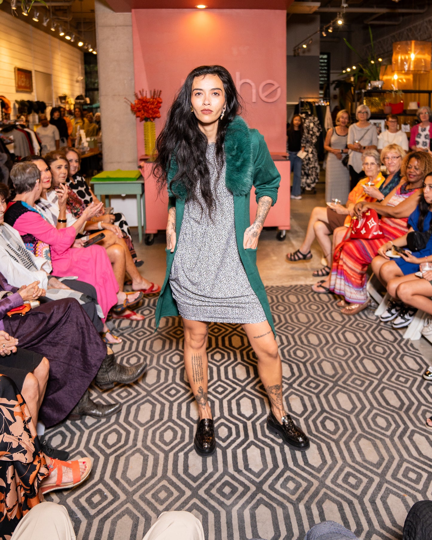 model walking down runway wearing speckled dress with a fur collar green cover up