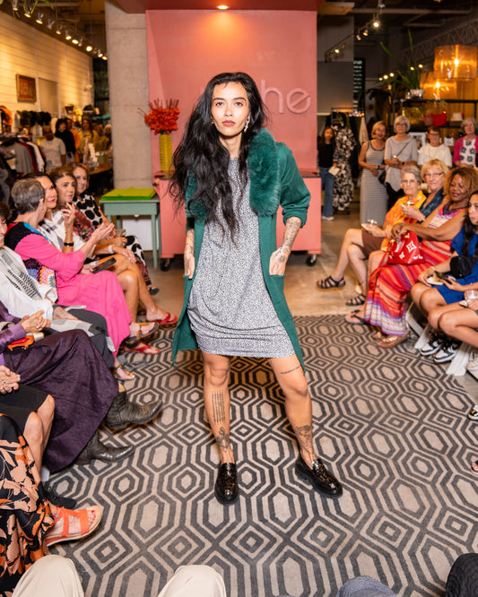 model walking down runway wearing speckled dress with a fur collar green cover up