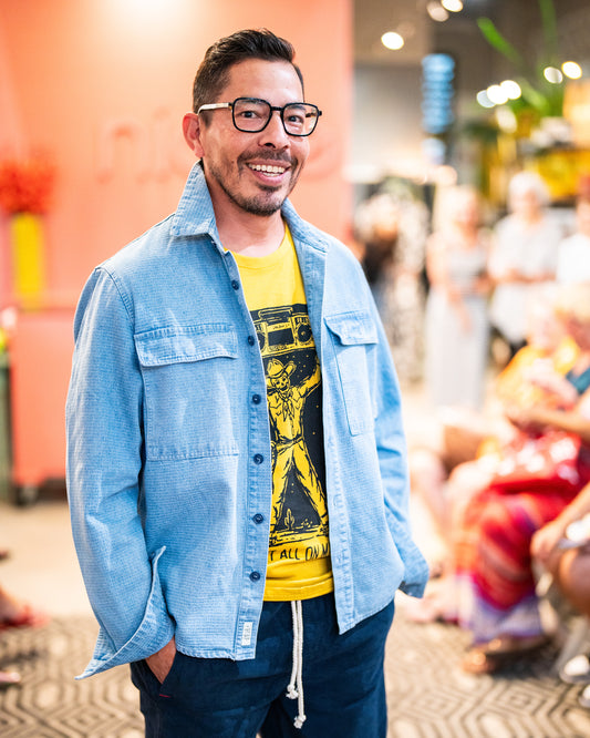 model in a denim shirt worn open over a yellow graphic tee and blue pants