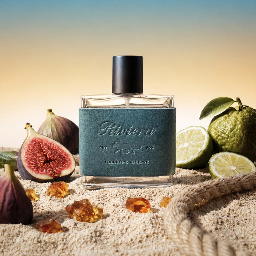 Perfume bottle labeled 'Riviera' with figs and limes on a sandy background
