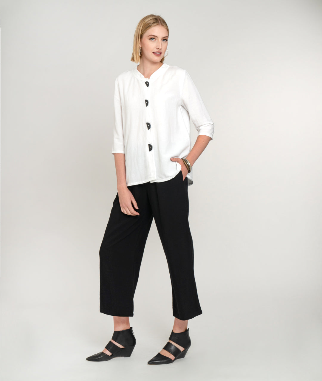 model in a wide leg black pant with a white button down jacket