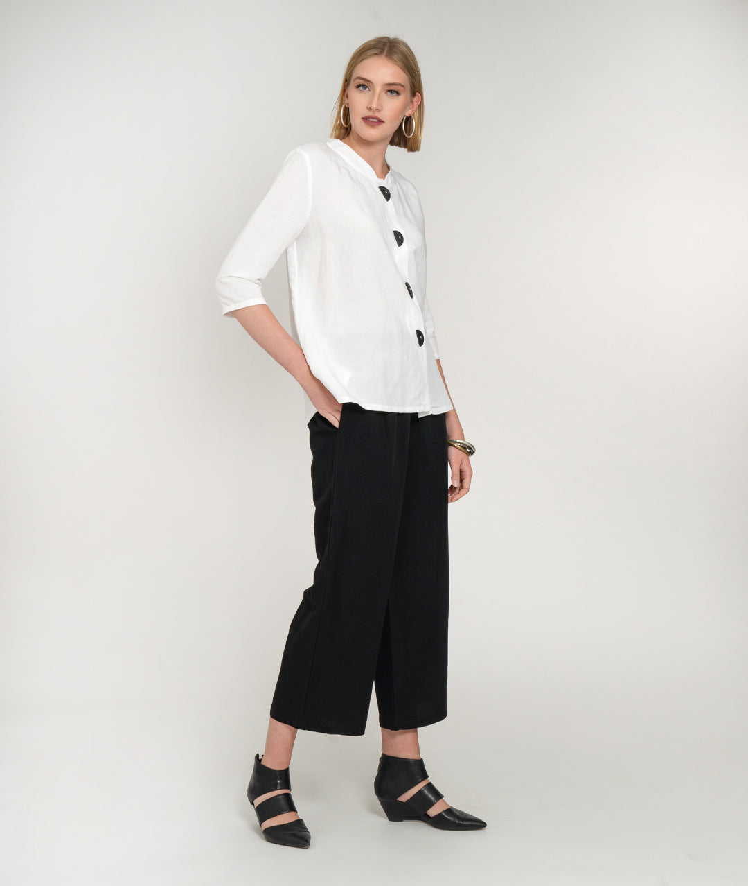 model in a wide leg black pant with a white button down jacket